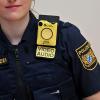 Eine Polizistin trägt nach einer Pressekonferenz eine sogenannte „Bodycam“ an ihrer Uniform.