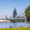 Ein Kajakfahrer rudert auf dem Rhein, im Hintergrund ist der Kölner Dom und die Severinbrücke zu sehen.