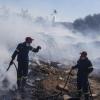 Feuerwehrleute versuchen, ein Feuer zu löschen, während ein Löschhubschrauber Wasser im Vorort Koropi im Osten von Athen abwirft.