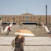 Eine Frau schützt sich mit einem Sonnenschirm  auf dem Syntagma-Platz in Athen vor der Sonne: Warme Luftmassen sorgen für Temperaturen von örtlich bis zu 45 Grad.