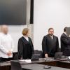 Zwei wegen Mordes angeklagte Männer (2.v.l.) und (2.v.r.) stehen zu Prozessbeginn im Sitzungssaal im Landgericht Nürnberg-Fürth zwischen ihren Anwälten.