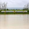 Ein Zug fährt an einer vom Regen überfluteten Wiese vorbei.