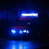 Ein Krankenwagen fährt mit Blaulicht durch eine Straße in der Nacht.