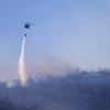 Ein Hubschrauber wirft Wasser auf einen Waldbrand im Norden Athens ab.