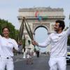 Olympia-Countdown: Fackelträger Nina Metayer, eine französische Konditorin, und Amir, ein französisch-israelischer Sänger, halten die olympische Fackel auf der Avenue des Champs-Elysees.