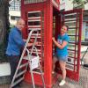 Restaurator Stefan Muck und Anni Sander vom Freundeskreis Ammersee Windermere bearbeiten die Bücher-Telefonzelle in Dießen. 