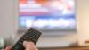 Eine Hand bedient eine Fernbedienung für ein TV-Gerät. Eine Hand bedient eine Fernbedienung für ein TV-Gerät.