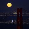 Hinter der Golden Gate Bridge ist am Himmel ein goldfarbener Vollmond zu sehen