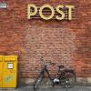 Ein Fahrrad steht vor einer Filiale der Postbank, die als Postfiliale fungiert. Anderswo in Deutschland gibt es keine Postfilialen, obwohl es sie einer staatlichen Vorschrift zufolge geben müsste.