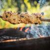 Ein Oliven-Feta-Knoblauch-Hefeteig ist um einen Haselnuss-Stock gewickelt und wird über dem Lagerfeuer gebacken.