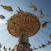 Auf dem Oktoberfest fliegen die Fahrgäste eine Runde im Kettenkarussell. 