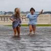 Camryn Frick (l) und Jillian Sternick aus Tampa halten sich an den Händen, als sie gemeinsam eine überflutete Straße am Bayshore Boulevard überqueren.