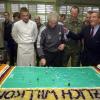 Rudi Völler (M) schneidet beim Truppenbesuch in Sarajevo eine Torte in Form eines Fußallplatzes an.