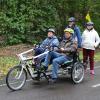 Roswita Götzfried sitzt neben ihrem Bruder Werner auf dem Fahrrad für zwei Personen. Dahinter stehen der Sozialpädagoge Christoph Schmid und eine Bewohnerin des Dominikus-Ringeisen-Werks.