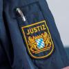 Auf der Uniform eines Justizbeamten ist das Bayerische Wappen und die Aufschrift „Justiz“ zu sehen. Betrüger geben sich immer wieder als falsche Justiz-Mitarbeiter aus. (Symbolbild)