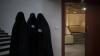 Drei in schwarzen Burkas gehüllte Frauen stehen vor einem Hörsaal der Universität in Kabul. Bei einer Demonstration zogen dutzende Frauen über das Gelände der Universität, wo sie ihre Unterstützung für die Regierung der militant-islamistischen Taliban vermittelten.