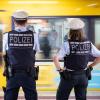 Polizeibeamte kontrollieren an einer Haltestelle im öffentlichen Nahverkehr die Einhaltung der Maskenpflicht. 