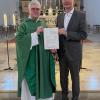 Abgeordneter Peter Tomaschko (rechts) übergab den Förderbescheid für die Wallfahrtskirche Herrgottsruh an Pater Hans-Joachim Winkens (links).