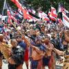 Demonstranten tragen die traditionelle Kleidung der indigenen Bevölkerung und präsentieren die Maori-Flagge,