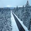 Ein Auto fährt am 18. November 2024 durch den Winterwald bei Tellerhäuser im Erzgebirge (Luftaufnahme mit Drohne). Mit Schneefall in den Mittelgebirgen und glatten Straßen hat sich auch in Sachsen der Winter bemerkbar gemacht. 