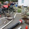 Um kurz nach 5 Uhr, am Tag der Deutschen Einheit, ist die Mindel in Jettingen (Landkreis Günzburg) übergelaufen und hat ein Wohngebiet überschwemmt. Offenbar war eine sogenannte Falle am Wasserkraftwerk defekt. Durch den starken Regen konnte nicht mehr genügend Wasser abfließen.

Wie Einsatzleiter und Kommandant der örtlichen Feuerwehr Markus Schmucker mitteilte, stand im "Korea", wie die Einheimischen das Wohngebiet am westlichen Ortsrand von Jettingen nennen, das Wasser auf den Straßen rund 20 Zentimeter hoch, als die Einsatzkräfte kamen. Und das Wasser stieg noch weiter.
Schleuse müssen geöffnet werdenAm ehemaligen Stauffenberg-Areal zwischen Mindellauf und Mindelkanal befindet sich ein Wasserkraftwerk mit zwei großen Fallen. Bei geringer ankommender Wassermenge sind beide Fallen geschlossen, um das Wasser komplett durch die Turbine zur Stromerzeugung zu leiten. Kommt aber eine so große Wassermenge von flussaufwärts an, dass das Wasser durch den alleinigen Durchfluss durch die Turbine nicht mehr abfließen kann, müssen die Fallen geöffnet werden, um ein Überlaufen der Mindel zu verhindern.Defekt an einer der SchleusenDie zweite Falle wird geöffnet, wenn notwendig. Wie der 2. Bürgermeister von Jettingen-Scheppach Hans Reichhardt berichtet, funktioniert diese zweite Falle seit geraumer Zeit allerdings nicht. Das Gestänge ist ausgehängt. Die Regenmengen am Montag waren so stark, dass das vom Oberlauf der Mindel ankommende Wasser nicht mehr genügend abgeleitet werden konnte. Das führte zum Ansteigen und schließlich zum Überlaufen der Mindel.Mindel läuft über!Das Wasser floss über mehrere Felder und überflutete schließlich das Wohngebiet bis zu einer Höhe von 1,20 Metern. Wie Reichhardt, der selbst ein Wasserkraftwerk betreibt, weiter ausführt, hatten Anwohner und die Gemeinde die Kraftwerksbetreiberin, die nicht im Landkreis wohnt, bereits dazu aufgefordert, die defekte Falle instand zu setzen. Dies sei leider bisher nicht geschehen, mit den nun entsprechenden Konsequenzen. Letztlich wurde ein von der Gemeinde betriebener Kanal geöffnet, über den eine große Wassermenge um das Wohngebiet herum abgeleitet werden kann.Große Schäden in PrivathäusernDie Familie Wolfmiller wohnt im Hammerschmiedweg und wurde vom Nachbarn gegen 6 Uhr angerufen und auf das Wasser aufmerksam gemacht. Wie der Vater sichtlich mitgenommen erklärt, hatte er dann mit einem Wassersauger im Keller das bereits dort angesammelte Wasser abgesaugt, als er plötzlich in einem Nebenraum ein Rauschen wahrnahm. Beim Nachschauen konnte er feststellen, dass dort die Bodenplatte des betonierten Kellers aufriss und das Wasser den Keller flutete. Neben Waschmaschine, Trockner und zwei Gefriertruhen ist auch der Speicher der Solaranlage im Keller. Alle Gerätschaften werden wohl komplett beschädigt worden sein.80 Kräfte im EinsatzZwischenzeitlich hatte der Einsatzleiter Schmucker u.a. noch die Feuerwehren Scheppach und Burgau nachalarmieren lassen. Insgesamt waren rund 80 Feuerwehrkräfte im Einsatz. Sie halfen mit rund 20 Tauch- und Tragkraftpumpen den Anwohnern beim vorsichtigen Auspumpen der Räumlichkeiten. Hier mussten die Einsatzkräfte aufpassen: Wenn der Wasserspiegel außen noch zu hoch ist, der Keller aber komplett leer gepumpt wird, wirkt ein großer Druck auf die Außenwände und die Bodenplatte eines Gebäudes. Das kann zu großen Schäden führen.Noch nie in diesem Ausmaß
Monika Wiesbauer, in deren Keller ebenfalls Wasser stand, zeigte ihren Garten. Dort hatte sie  noch am Sonntag Holz aufgestapelt und Blumen gerichtet. Nun steht dort das Wasser mehrere Zentimeter hoch. Die 68-Jährige wohnt dort seit 1958 und hat schon einige Male miterlebt, wie das Wasser aus dem Boden in den Keller gedrückt wurde. Dass es aber von oben in den Keller läuft und noch dazu in diesem Ausmaß, das gab es noch nie. Sie wurde gegen 6.30 Uhr von ihrem Nachbarn geweckt mit den Worten "Monika mach auf, da kommt 's Wasser." Doch viel dagegen tun konnte sie nicht. Hochwassergebiet ausgewiesenAuf die betroffenen Anwohner kommt eine schwere Zeit zu. Das Gebiet ist als Hochwassergebiet ausgewiesen. Daher ist es nicht möglich, ihre Häuser gegen solche Schäden zu versichern. Zudem müssen sie nun versuchen, die wassergetränkten Wände wieder trocken zu bekommen, was bei den aktuellen und weiter steigenden Energiekosten nochmals eine große Herausforderung darstellt. Ganz abgesehen von den beschädigten Gerätschaften und Heizungsanlagen.