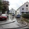 Um kurz nach 5 Uhr, am Tag der Deutschen Einheit, ist die Mindel in Jettingen (Landkreis Günzburg) übergelaufen und hat ein Wohngebiet überschwemmt. Offenbar war eine sogenannte Falle am Wasserkraftwerk defekt. Durch den starken Regen konnte nicht mehr genügend Wasser abfließen.

Wie Einsatzleiter und Kommandant der örtlichen Feuerwehr Markus Schmucker mitteilte, stand im "Korea", wie die Einheimischen das Wohngebiet am westlichen Ortsrand von Jettingen nennen, das Wasser auf den Straßen rund 20 Zentimeter hoch, als die Einsatzkräfte kamen. Und das Wasser stieg noch weiter.
Schleuse müssen geöffnet werdenAm ehemaligen Stauffenberg-Areal zwischen Mindellauf und Mindelkanal befindet sich ein Wasserkraftwerk mit zwei großen Fallen. Bei geringer ankommender Wassermenge sind beide Fallen geschlossen, um das Wasser komplett durch die Turbine zur Stromerzeugung zu leiten. Kommt aber eine so große Wassermenge von flussaufwärts an, dass das Wasser durch den alleinigen Durchfluss durch die Turbine nicht mehr abfließen kann, müssen die Fallen geöffnet werden, um ein Überlaufen der Mindel zu verhindern.Defekt an einer der SchleusenDie zweite Falle wird geöffnet, wenn notwendig. Wie der 2. Bürgermeister von Jettingen-Scheppach Hans Reichhardt berichtet, funktioniert diese zweite Falle seit geraumer Zeit allerdings nicht. Das Gestänge ist ausgehängt. Die Regenmengen am Montag waren so stark, dass das vom Oberlauf der Mindel ankommende Wasser nicht mehr genügend abgeleitet werden konnte. Das führte zum Ansteigen und schließlich zum Überlaufen der Mindel.Mindel läuft über!Das Wasser floss über mehrere Felder und überflutete schließlich das Wohngebiet bis zu einer Höhe von 1,20 Metern. Wie Reichhardt, der selbst ein Wasserkraftwerk betreibt, weiter ausführt, hatten Anwohner und die Gemeinde die Kraftwerksbetreiberin, die nicht im Landkreis wohnt, bereits dazu aufgefordert, die defekte Falle instand zu setzen. Dies sei leider bisher nicht geschehen, mit den nun entsprechenden Konsequenzen. Letztlich wurde ein von der Gemeinde betriebener Kanal geöffnet, über den eine große Wassermenge um das Wohngebiet herum abgeleitet werden kann.Große Schäden in PrivathäusernDie Familie Wolfmiller wohnt im Hammerschmiedweg und wurde vom Nachbarn gegen 6 Uhr angerufen und auf das Wasser aufmerksam gemacht. Wie der Vater sichtlich mitgenommen erklärt, hatte er dann mit einem Wassersauger im Keller das bereits dort angesammelte Wasser abgesaugt, als er plötzlich in einem Nebenraum ein Rauschen wahrnahm. Beim Nachschauen konnte er feststellen, dass dort die Bodenplatte des betonierten Kellers aufriss und das Wasser den Keller flutete. Neben Waschmaschine, Trockner und zwei Gefriertruhen ist auch der Speicher der Solaranlage im Keller. Alle Gerätschaften werden wohl komplett beschädigt worden sein.80 Kräfte im EinsatzZwischenzeitlich hatte der Einsatzleiter Schmucker u.a. noch die Feuerwehren Scheppach und Burgau nachalarmieren lassen. Insgesamt waren rund 80 Feuerwehrkräfte im Einsatz. Sie halfen mit rund 20 Tauch- und Tragkraftpumpen den Anwohnern beim vorsichtigen Auspumpen der Räumlichkeiten. Hier mussten die Einsatzkräfte aufpassen: Wenn der Wasserspiegel außen noch zu hoch ist, der Keller aber komplett leer gepumpt wird, wirkt ein großer Druck auf die Außenwände und die Bodenplatte eines Gebäudes. Das kann zu großen Schäden führen.Noch nie in diesem Ausmaß
Monika Wiesbauer, in deren Keller ebenfalls Wasser stand, zeigte ihren Garten. Dort hatte sie  noch am Sonntag Holz aufgestapelt und Blumen gerichtet. Nun steht dort das Wasser mehrere Zentimeter hoch. Die 68-Jährige wohnt dort seit 1958 und hat schon einige Male miterlebt, wie das Wasser aus dem Boden in den Keller gedrückt wurde. Dass es aber von oben in den Keller läuft und noch dazu in diesem Ausmaß, das gab es noch nie. Sie wurde gegen 6.30 Uhr von ihrem Nachbarn geweckt mit den Worten "Monika mach auf, da kommt 's Wasser." Doch viel dagegen tun konnte sie nicht. Hochwassergebiet ausgewiesenAuf die betroffenen Anwohner kommt eine schwere Zeit zu. Das Gebiet ist als Hochwassergebiet ausgewiesen. Daher ist es nicht möglich, ihre Häuser gegen solche Schäden zu versichern. Zudem müssen sie nun versuchen, die wassergetränkten Wände wieder trocken zu bekommen, was bei den aktuellen und weiter steigenden Energiekosten nochmals eine große Herausforderung darstellt. Ganz abgesehen von den beschädigten Gerätschaften und Heizungsanlagen.