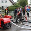Um kurz nach 5 Uhr, am Tag der Deutschen Einheit, ist die Mindel in Jettingen (Landkreis Günzburg) übergelaufen und hat ein Wohngebiet überschwemmt. Offenbar war eine sogenannte Falle am Wasserkraftwerk defekt. Durch den starken Regen konnte nicht mehr genügend Wasser abfließen.

Wie Einsatzleiter und Kommandant der örtlichen Feuerwehr Markus Schmucker mitteilte, stand im "Korea", wie die Einheimischen das Wohngebiet am westlichen Ortsrand von Jettingen nennen, das Wasser auf den Straßen rund 20 Zentimeter hoch, als die Einsatzkräfte kamen. Und das Wasser stieg noch weiter.
Schleuse müssen geöffnet werdenAm ehemaligen Stauffenberg-Areal zwischen Mindellauf und Mindelkanal befindet sich ein Wasserkraftwerk mit zwei großen Fallen. Bei geringer ankommender Wassermenge sind beide Fallen geschlossen, um das Wasser komplett durch die Turbine zur Stromerzeugung zu leiten. Kommt aber eine so große Wassermenge von flussaufwärts an, dass das Wasser durch den alleinigen Durchfluss durch die Turbine nicht mehr abfließen kann, müssen die Fallen geöffnet werden, um ein Überlaufen der Mindel zu verhindern.Defekt an einer der SchleusenDie zweite Falle wird geöffnet, wenn notwendig. Wie der 2. Bürgermeister von Jettingen-Scheppach Hans Reichhardt berichtet, funktioniert diese zweite Falle seit geraumer Zeit allerdings nicht. Das Gestänge ist ausgehängt. Die Regenmengen am Montag waren so stark, dass das vom Oberlauf der Mindel ankommende Wasser nicht mehr genügend abgeleitet werden konnte. Das führte zum Ansteigen und schließlich zum Überlaufen der Mindel.Mindel läuft über!Das Wasser floss über mehrere Felder und überflutete schließlich das Wohngebiet bis zu einer Höhe von 1,20 Metern. Wie Reichhardt, der selbst ein Wasserkraftwerk betreibt, weiter ausführt, hatten Anwohner und die Gemeinde die Kraftwerksbetreiberin, die nicht im Landkreis wohnt, bereits dazu aufgefordert, die defekte Falle instand zu setzen. Dies sei leider bisher nicht geschehen, mit den nun entsprechenden Konsequenzen. Letztlich wurde ein von der Gemeinde betriebener Kanal geöffnet, über den eine große Wassermenge um das Wohngebiet herum abgeleitet werden kann.Große Schäden in PrivathäusernDie Familie Wolfmiller wohnt im Hammerschmiedweg und wurde vom Nachbarn gegen 6 Uhr angerufen und auf das Wasser aufmerksam gemacht. Wie der Vater sichtlich mitgenommen erklärt, hatte er dann mit einem Wassersauger im Keller das bereits dort angesammelte Wasser abgesaugt, als er plötzlich in einem Nebenraum ein Rauschen wahrnahm. Beim Nachschauen konnte er feststellen, dass dort die Bodenplatte des betonierten Kellers aufriss und das Wasser den Keller flutete. Neben Waschmaschine, Trockner und zwei Gefriertruhen ist auch der Speicher der Solaranlage im Keller. Alle Gerätschaften werden wohl komplett beschädigt worden sein.80 Kräfte im EinsatzZwischenzeitlich hatte der Einsatzleiter Schmucker u.a. noch die Feuerwehren Scheppach und Burgau nachalarmieren lassen. Insgesamt waren rund 80 Feuerwehrkräfte im Einsatz. Sie halfen mit rund 20 Tauch- und Tragkraftpumpen den Anwohnern beim vorsichtigen Auspumpen der Räumlichkeiten. Hier mussten die Einsatzkräfte aufpassen: Wenn der Wasserspiegel außen noch zu hoch ist, der Keller aber komplett leer gepumpt wird, wirkt ein großer Druck auf die Außenwände und die Bodenplatte eines Gebäudes. Das kann zu großen Schäden führen.Noch nie in diesem Ausmaß
Monika Wiesbauer, in deren Keller ebenfalls Wasser stand, zeigte ihren Garten. Dort hatte sie  noch am Sonntag Holz aufgestapelt und Blumen gerichtet. Nun steht dort das Wasser mehrere Zentimeter hoch. Die 68-Jährige wohnt dort seit 1958 und hat schon einige Male miterlebt, wie das Wasser aus dem Boden in den Keller gedrückt wurde. Dass es aber von oben in den Keller läuft und noch dazu in diesem Ausmaß, das gab es noch nie. Sie wurde gegen 6.30 Uhr von ihrem Nachbarn geweckt mit den Worten "Monika mach auf, da kommt 's Wasser." Doch viel dagegen tun konnte sie nicht. Hochwassergebiet ausgewiesenAuf die betroffenen Anwohner kommt eine schwere Zeit zu. Das Gebiet ist als Hochwassergebiet ausgewiesen. Daher ist es nicht möglich, ihre Häuser gegen solche Schäden zu versichern. Zudem müssen sie nun versuchen, die wassergetränkten Wände wieder trocken zu bekommen, was bei den aktuellen und weiter steigenden Energiekosten nochmals eine große Herausforderung darstellt. Ganz abgesehen von den beschädigten Gerätschaften und Heizungsanlagen.