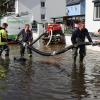 Um kurz nach 5 Uhr, am Tag der Deutschen Einheit, ist die Mindel in Jettingen (Landkreis Günzburg) übergelaufen und hat ein Wohngebiet überschwemmt. Offenbar war eine sogenannte Falle am Wasserkraftwerk defekt. Durch den starken Regen konnte nicht mehr genügend Wasser abfließen.

Wie Einsatzleiter und Kommandant der örtlichen Feuerwehr Markus Schmucker mitteilte, stand im "Korea", wie die Einheimischen das Wohngebiet am westlichen Ortsrand von Jettingen nennen, das Wasser auf den Straßen rund 20 Zentimeter hoch, als die Einsatzkräfte kamen. Und das Wasser stieg noch weiter.
Schleuse müssen geöffnet werdenAm ehemaligen Stauffenberg-Areal zwischen Mindellauf und Mindelkanal befindet sich ein Wasserkraftwerk mit zwei großen Fallen. Bei geringer ankommender Wassermenge sind beide Fallen geschlossen, um das Wasser komplett durch die Turbine zur Stromerzeugung zu leiten. Kommt aber eine so große Wassermenge von flussaufwärts an, dass das Wasser durch den alleinigen Durchfluss durch die Turbine nicht mehr abfließen kann, müssen die Fallen geöffnet werden, um ein Überlaufen der Mindel zu verhindern.Defekt an einer der SchleusenDie zweite Falle wird geöffnet, wenn notwendig. Wie der 2. Bürgermeister von Jettingen-Scheppach Hans Reichhardt berichtet, funktioniert diese zweite Falle seit geraumer Zeit allerdings nicht. Das Gestänge ist ausgehängt. Die Regenmengen am Montag waren so stark, dass das vom Oberlauf der Mindel ankommende Wasser nicht mehr genügend abgeleitet werden konnte. Das führte zum Ansteigen und schließlich zum Überlaufen der Mindel.Mindel läuft über!Das Wasser floss über mehrere Felder und überflutete schließlich das Wohngebiet bis zu einer Höhe von 1,20 Metern. Wie Reichhardt, der selbst ein Wasserkraftwerk betreibt, weiter ausführt, hatten Anwohner und die Gemeinde die Kraftwerksbetreiberin, die nicht im Landkreis wohnt, bereits dazu aufgefordert, die defekte Falle instand zu setzen. Dies sei leider bisher nicht geschehen, mit den nun entsprechenden Konsequenzen. Letztlich wurde ein von der Gemeinde betriebener Kanal geöffnet, über den eine große Wassermenge um das Wohngebiet herum abgeleitet werden kann.Große Schäden in PrivathäusernDie Familie Wolfmiller wohnt im Hammerschmiedweg und wurde vom Nachbarn gegen 6 Uhr angerufen und auf das Wasser aufmerksam gemacht. Wie der Vater sichtlich mitgenommen erklärt, hatte er dann mit einem Wassersauger im Keller das bereits dort angesammelte Wasser abgesaugt, als er plötzlich in einem Nebenraum ein Rauschen wahrnahm. Beim Nachschauen konnte er feststellen, dass dort die Bodenplatte des betonierten Kellers aufriss und das Wasser den Keller flutete. Neben Waschmaschine, Trockner und zwei Gefriertruhen ist auch der Speicher der Solaranlage im Keller. Alle Gerätschaften werden wohl komplett beschädigt worden sein.80 Kräfte im EinsatzZwischenzeitlich hatte der Einsatzleiter Schmucker u.a. noch die Feuerwehren Scheppach und Burgau nachalarmieren lassen. Insgesamt waren rund 80 Feuerwehrkräfte im Einsatz. Sie halfen mit rund 20 Tauch- und Tragkraftpumpen den Anwohnern beim vorsichtigen Auspumpen der Räumlichkeiten. Hier mussten die Einsatzkräfte aufpassen: Wenn der Wasserspiegel außen noch zu hoch ist, der Keller aber komplett leer gepumpt wird, wirkt ein großer Druck auf die Außenwände und die Bodenplatte eines Gebäudes. Das kann zu großen Schäden führen.Noch nie in diesem Ausmaß
Monika Wiesbauer, in deren Keller ebenfalls Wasser stand, zeigte ihren Garten. Dort hatte sie  noch am Sonntag Holz aufgestapelt und Blumen gerichtet. Nun steht dort das Wasser mehrere Zentimeter hoch. Die 68-Jährige wohnt dort seit 1958 und hat schon einige Male miterlebt, wie das Wasser aus dem Boden in den Keller gedrückt wurde. Dass es aber von oben in den Keller läuft und noch dazu in diesem Ausmaß, das gab es noch nie. Sie wurde gegen 6.30 Uhr von ihrem Nachbarn geweckt mit den Worten "Monika mach auf, da kommt 's Wasser." Doch viel dagegen tun konnte sie nicht. Hochwassergebiet ausgewiesenAuf die betroffenen Anwohner kommt eine schwere Zeit zu. Das Gebiet ist als Hochwassergebiet ausgewiesen. Daher ist es nicht möglich, ihre Häuser gegen solche Schäden zu versichern. Zudem müssen sie nun versuchen, die wassergetränkten Wände wieder trocken zu bekommen, was bei den aktuellen und weiter steigenden Energiekosten nochmals eine große Herausforderung darstellt. Ganz abgesehen von den beschädigten Gerätschaften und Heizungsanlagen.