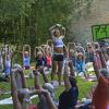 Nadja Ehlert (Mitte) macht eine Übung vor, bei der die Teilnehmer die Arme so weit nach oben strecken sollen, wie möglich. Das stärkt und dehnt den Rücken. Etwa 120 Yoga-Begeisterte machen im Stadtpark Neue Welt mit.