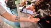 Ein Mitarbeiter eines Cafés überprüft das temporäre Tattoo einer Frau mit einem QR-Code, um ihr COVID-19 in Moskau, Russland, zu überprüfen. 
