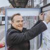 Landrat Thomas Eichinger (CSU) hängt einen der neuen MVV-Fahrpläne symbolisch in einen Schaukasten am Busbahnhof in Landsberg. 