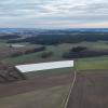 Die Luftaufnahme zeigt, wo der Solarpark „Kühbach IV“ gebaut werden soll (weiß eingezeichnet). Im Hintergrund ist das Waldstück Scharnitz zu sehen, wo der Windpark „Scharnitz“ mit sechs Windrädern entsteht.