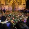 Mehrere Menschen legen Blumen und Kerzen am offiziellen Gedenkort an der Johanniskirche nieder.