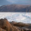 Zwei Studenten der New York University sitzen auf einem Felsen mit Blick auf den grönländischen Helheim-Gletscher.