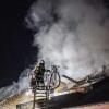 Ein Feuerwehrmann löscht den Brand in einem Mehrfamilienhaus.