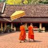 Mönche tragen einen Prozessionsschirm im Wat Si Saket, einem bedeutenden Tempel in Vientiane, der Hauptstadt von Laos.