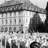 Fronleichnamsprozession 1943: Am Adolf-Hitler-Platz (heute Barbarossaplatz) ziehen Mädchen in ihren Kommunionkleidern vorbei. Vor dem Juliusspital
wirbt die Attrappe einer Fliegerbombe bei der Bevölkerung für die Luftschutzmaßnahmen.