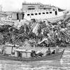 Ein traditionelles Fischerboot fährt vor einem Trümmerfeld mit einem gestrandeten Schiff vorbei, das von der
Tsunami-Welle zerstört wurde. Mehr als 220 000 Menschen verloren bei dem Tsunami vor einem halben Jahr ihr
Leben.