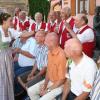 Angela I., Weinprinzessin aus Neuses am Berg, „vermisst“ die Größe der kahlen Kopffläche der Glatzenkandidaten mit ihrer Handfläche. Gerade legt sie Bernd aus der Oberlausitz, dem späteren Sieger, ihre Hand auf. Ganz rechts harrt Manfred aus Nürnberg, der ebenfalls den ersten Platz bei der Glatzenprämierung erzielte, auf die Handauflegung und die Glatzentaufe. Im Hintergrund links verfolgt Dettelbachs Weinprinzessin Eva I. schmunzelnd das Geschehen.