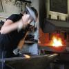 Vollen Körpereinsatz gibt Metallgestalterin Tanja Seger bei der Arbeit mit Hammer und Metall am Amboss.