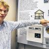 Der wissenschaftliche Mitarbeiter des Fraunhofer Instituts für Solare Energiesysteme (ISE) in Freiburg, Stefan Feuerhahn, steht in einem Laborraum des Instituts vor einer Tafel mit dem Haus der Zukunft.