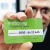 Ein Mitarbeiter des Vereins „Mobbing keine Chance e. V“ zeigt im Stuttgarter Landesbüro eine Kontakt-Karte mit der Hotline des „Mobbing Competence Center Baden-Württemberg“.