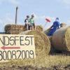 Mit diesem Traktor aus Stroh weisen die Bewohner der Grünsfelder Siedlung am Ortseingang von Urspringen auf das Fest hin (Leon und Felix testen schon einmal den Traktor).
