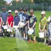 Künstlicher Regen: Dr. Gerhard Lung sprüht das Wasser-Biodyozon-Gemisch auf den Karbacher Fußballplatz, beobachtet von zahlreichen Kindern und gefilmt von BR-Kamerafrau Angela Witt.