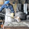 Schwere Handarbeit: Beim Nachguss ergänzt Gießereimeister Holger Winkler fehlende Schmelze, bevor das Werkstück in der Sandform abkühlen kann.