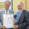 Feierstunde in der Synagoge: Landrat Reinhard Frank (links) übergibt den Ehrenpreis des Main-Tauber-Kreises samt Urkunde an Pfarrar Johannes Ghiraldin.