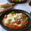 Kein Mischmasch: Die selbstgemachten Ravioli thronen beim Servieren auf der Tomatensoße.  Basilikumblätter sorgen für einen Farbtupfer.