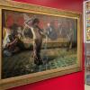 Blick in die Ausstellung mit dem Gemälde „Arabischer Schleiertanz“ (1893) des Malers Ferdinand Max Bredt sowie Bleiglasfenstern und Stühlen um 1900