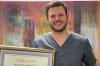 Dr. Matthias Klum zeigt stolz seinen "Meisterbrief" und den 1. Preis für die beste Masterthese.