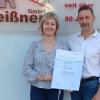 Daniela Jooß und Gunnar Meißner mit der Ehrenurkunde vor dem elterlichen Betrieb.